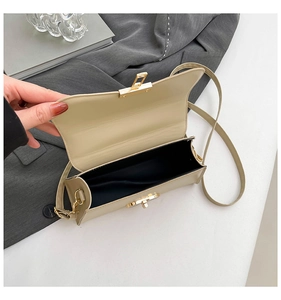 Detail view of small crossbody bag showing black satin interior and golden twist lock