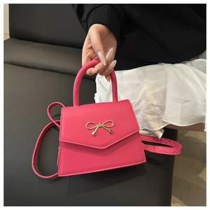 Detailaufnahme einer leuchtend rosa Mini-Umhängetasche mit goldener Schleifenschnalle