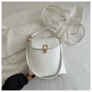Detail of white leather crossbody bag with distinctive gold teardrop-shaped metal twist lock