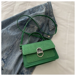 Detail of green crossbody bag with textured glitter flap and silver U-shaped metal buckle