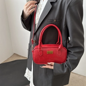 Red vintage leather bowling bag with gold plaque and top handles for crossbody wear