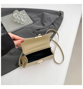 Detailed view of beige crossbody bag with gold clasp and dark interior lining