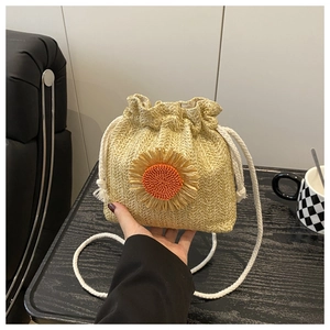 Detailed macro view of straw drawstring bucket bag featuring handcrafted sunflower decor