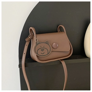 Detailed view of a brown small square crossbody bag with a round button and bear charm