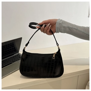 Detail of black crocodile pattern baguette bag with golden hardware and zipper closure