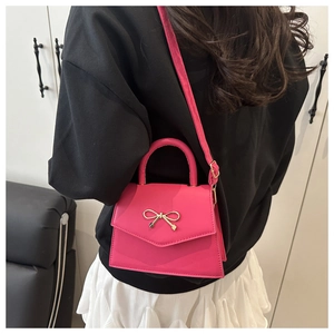 Detailed back view of a rose pink handbag with a golden bow buckle on a crossbody strap