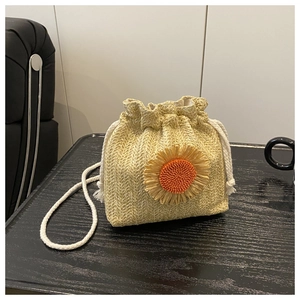 Détail d'un sac seau en paille avec une fleur de tournesol et cordon de serrage