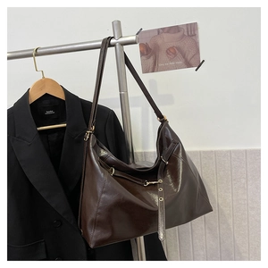 Detail of dark brown leather hobo bag with metallic ring buckle on a stylish hanger