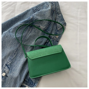 Detail of green crossbody bag showing mixed textures of PU leather and woven flap finish