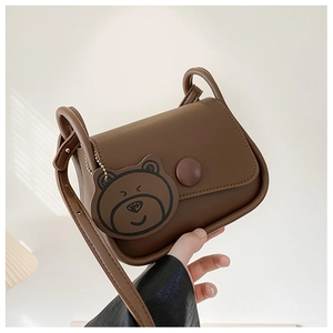 Close-up of brown mini crossbody bag with matte texture and cute bear pendant charm