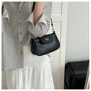 Close-up of black PU leather shoulder bag featuring a silver metal bow buckle detail