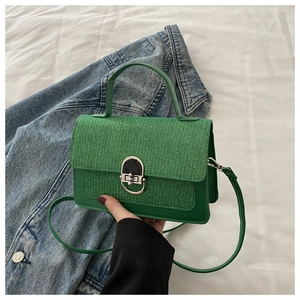 Detail of green handbag showing glitter texture cover, smooth leather and silver swivel lock