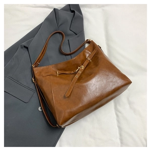 Detail of a brown vintage tote bag showing premium faux leather texture and gold buckle