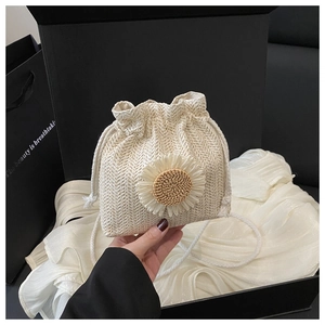 Détail d'un sac seau en paille beige avec marguerite blanche et texture tissée en coffret