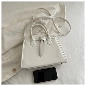 Detailed view of cream textured leather handbag with a stylish metal clasp closure
