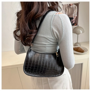 Detail showing the black faux leather crocodile pattern and gold zipper on underarm bag