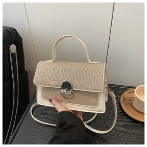 Detail of glittery flap texture and silver metal D-ring buckle on cream crossbody bag