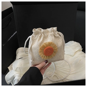 Détail d'un sac seau en paille tressé avec grande fleur de tournesol et anses en coton