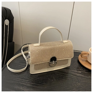 Close-up of glitter-covered flap and silver twist lock on cream white crossbody bag