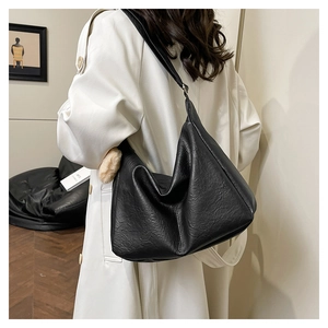 Close-up of a large black leather tote bag featuring a textured lychee grain finish