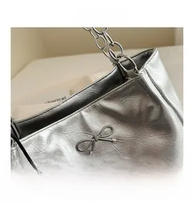 Macro shot of silver metallic leather tote with crinkled texture and bow hardware