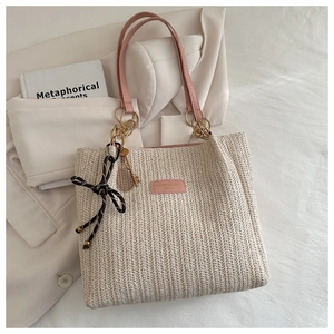 Close-up of woven tote bag with pink straps, tennis racket charm and decorative bow