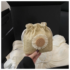Détail du sac seau en paille tissée avec une grande fleur de marguerite blanche en relief