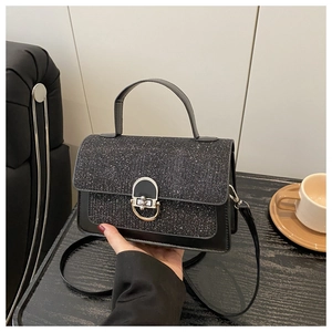 Close-up of a stylish black sequin handbag with a metallic lock in a cafe setting