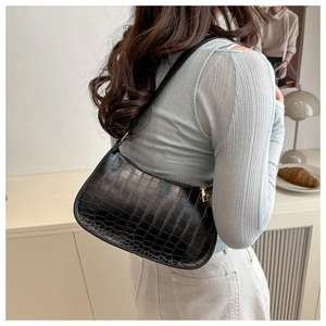 Close-up of black faux crocodile skin texture and golden zipper detail on the shoulder bag