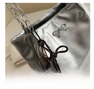 Close-up of silver tote bag featuring metallic pleats, bow detail, and chain strap