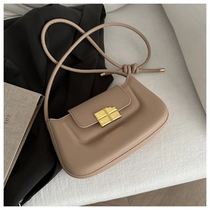Close-up of golden square cross metal lock on a khaki leather crossbody handbag