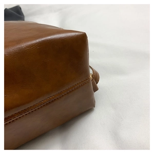 Detail of reinforced stitching and corner structure on a vintage brown leather tote bag
