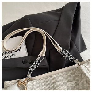Détail du sac tissé blanc avec bandoulière en chaîne argentée et pompon décoratif