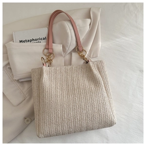 Detail of herringbone weave straw tote with pink leather handles and gold chain hardware