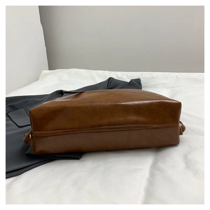 Close-up of vintage brown leather tote bag showing wide base and metallic ring detail