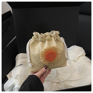 Détail d'un sac seau en paille bohème avec décor de tournesol et cordon de serrage