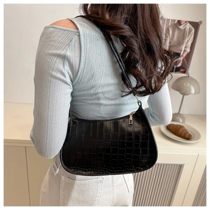 Close-up of black crocodile pattern baguette bag worn as a shoulder underarm bag