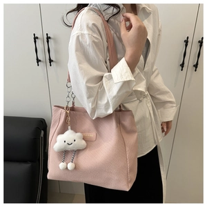 Pink corduroy tote bag with cloud charm detail on shoulder shown in lifestyle setting