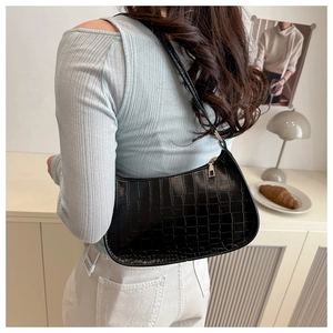 Close-up of black crocodile pattern faux leather underarm bag with glossy finish