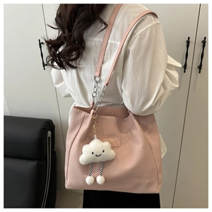 Detail of pink corduroy tote bag with silver chain strap and plush cloud charm