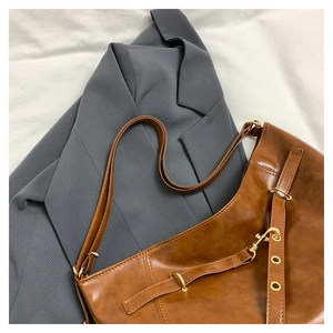 Detail of a brown vintage tote bag with gold metal hardware and adjustable strap