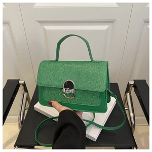 Detail of a bright green square flap bag featuring a sequin texture and horseshoe buckle