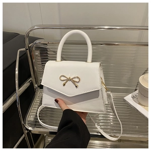 Details der weißen Mini-Umhängetasche mit goldener Schleifenschnalle und elegantem Griff