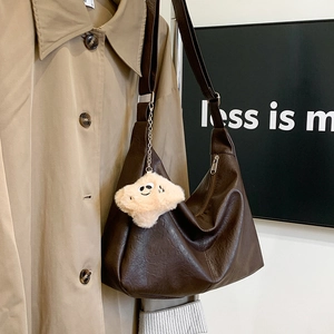 Detail of dark brown vintage faux leather tote bag with plush smiley face charm