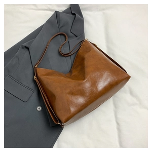 Flat lay of brown vintage tote bag with glossy finish on a grey suit and white fabric