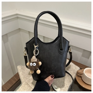Detail of black leather tote bag with monster charm on a cozy coffee table background