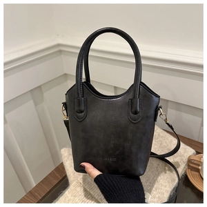 Detail of the black minimalist bucket bag featuring FASHION & BAGS logo and round handle