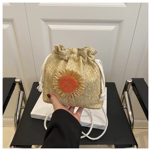 Detail of straw bucket bag featuring a sunflower ornament and white cotton drawstring closure
