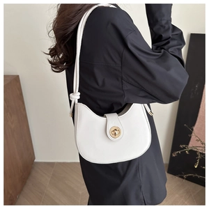 Detail of white half-moon underarm bag with gold metal clasp and knot strap design
