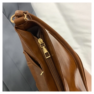 Detail shot of brown vintage tote bag showing glossy leather texture and gold zipper